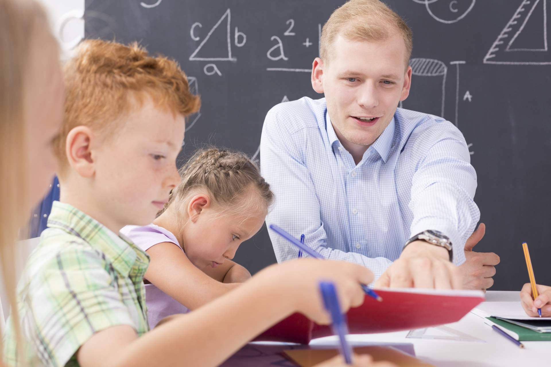 Teacher at table with younger student learning Math